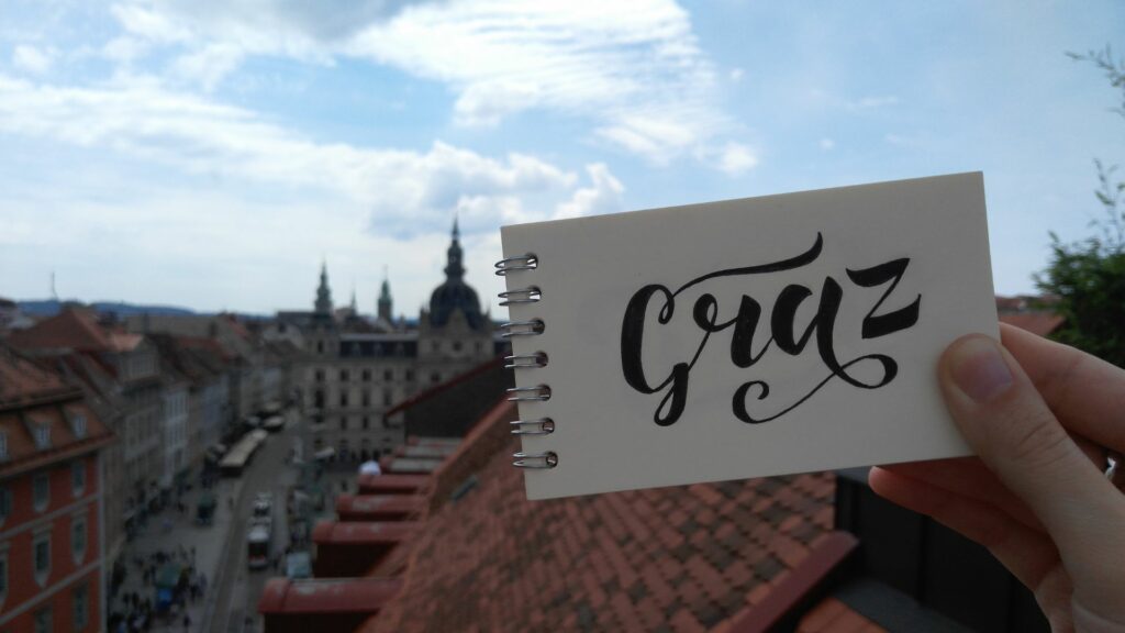 Hand mit Karte, auf der Graz steht. Immobilienstandort in Graz beim Kauf und Verkauf von Immobilien